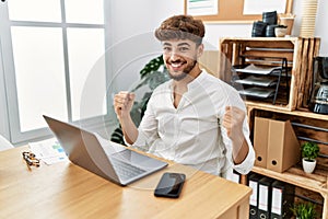 Young arab man working using computer laptop at the office screaming proud, celebrating victory and success very excited with