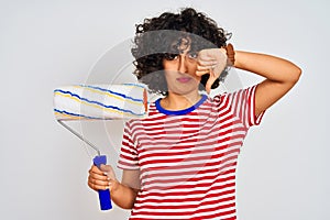 Young arab painter woman with curly hair holding paint roller over isolated white background with angry face, negative sign