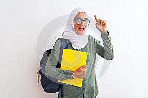 Young Arab student woman wearing hijab and backpack holding a book over isolated background surprised with an idea or question