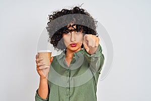 Young arab woman with curly hair drinking cup of coffee over isolated white background pointing with finger to the camera and to