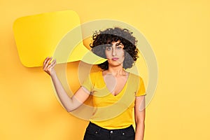 Young arab woman with curly hair holding speech bubble over isolated yellow background with a confident expression on smart face