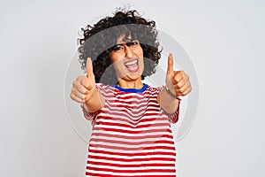 Young arab woman with curly hair wearing striped t-shirt over isolated white background approving doing positive gesture with