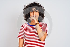 Young arab woman with curly hair wearing striped t-shirt over isolated white background asking to be quiet with finger on lips