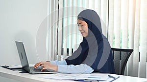 Young arab woman is happily sitting in the office