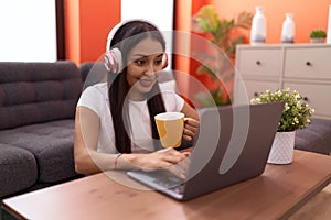 Young arab woman listening to music drinking coffee at home