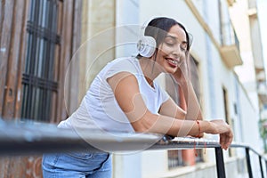 Young arab woman listening to music leaning on balustrade at street