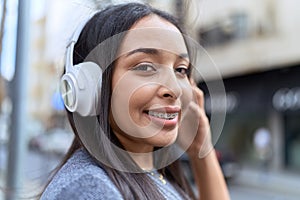 Young arab woman smiling confident listening to music at street