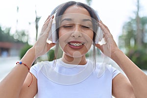 Young arab woman smiling confident listening to music at street
