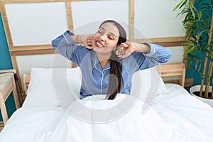 Young arab woman waking up stretching arms at bedroom