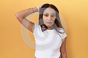 Young arab woman wearing casual white t shirt over yellow background confuse and wondering about question