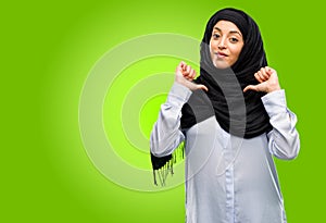 Young arab woman wearing hijab isolated over green background