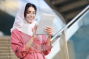 Young Arab woman wearing hijab using digital tablet outdoors