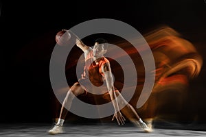 Young arabian basketball player of team in action, motion isolated on black background in mixed light. Concept of sport