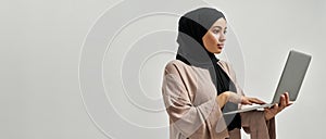 Young arabian girl in hijab working on laptop