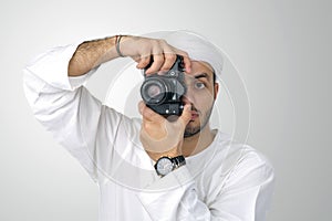 Young Arabian man using holding his camera ready to shoot, isolated