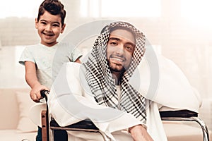 Young Arabian Man on Wheelchair with Smiling Son