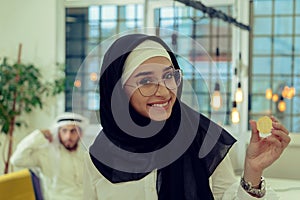 Young arabian muslim woman in hijab black clothes hold in hand holding bitcoin. C