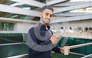 Young Arabic businessman using his phone gadget in urban area