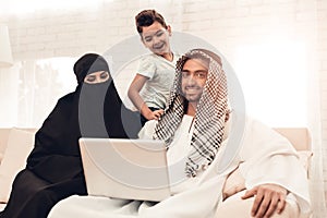 Young Arabic Family Using Laptop on Sofa at Home