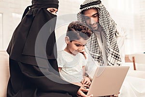 Young Arabic Family Using Laptop on Sofa at Home