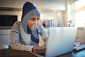 Young Arabic woman looking surprised while working online from h