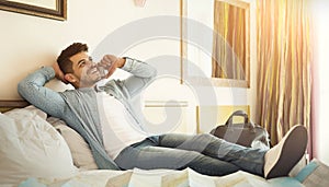 Young arabic man traveller lying on bed and talking on phone