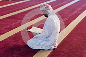 Young Arabic Muslim man reading Koran and praying. Religious muslim man reading holy koran inside the mosque