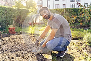 Young arabic smiling bearded farmer working in urban horticultural flower garden