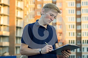 Young architect or engineer checking a building plan on site.