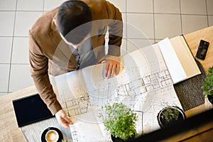 Young architect looking at building floor plans. High angle view