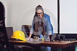 Young architect looking at papers before going outside at construction site. - Image