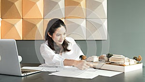 Young architect measure house model while taking a note blueprint. Manipulator.