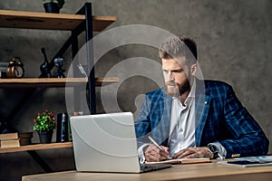 Young architect work project. Photo of bearded man working with new startup project in modern loft office. Generic design notebook