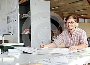 Young architect working on drawing table in architect studio.