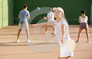 Young Argentinian woman playing pelota at open-air fronton in summer