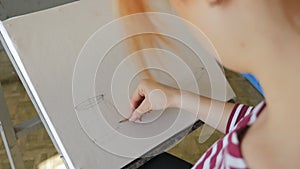 A young artist in an art workshop draws a still life of a sketch from nature in pencil.