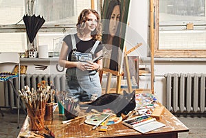 Young artist in his Studio painting a picture. Female hands of the young artist and oil paint