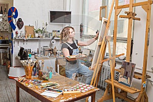 Young artist in his Studio painting a picture. Female hands of the young artist and oil paint