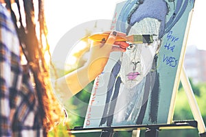 Young artist painting a self portrait in a park outdoor - Close up of painter with dreadlocks hairstyle working on her art