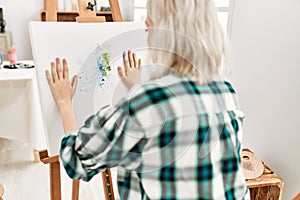 Young artist student girl on back view painting canvas with painted hands at art studio