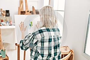 Young artist student girl on back view painting canvas with painted hands at art studio