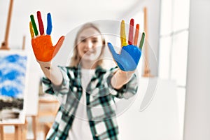 Young artist student girl smiling happy showing colorful painted hands at art studio