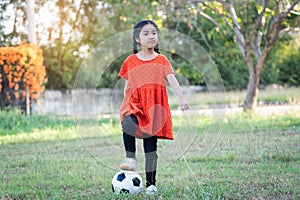 A young Asain girl playing football with her big black dog outside the grass ground in the yard in the evening