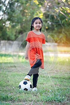 A young Asain girl playing football with her big black dog outside the grass ground in the yard in the evening