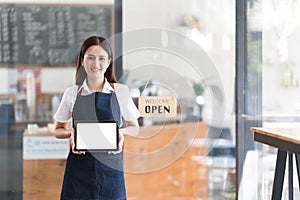 Young asia business owner woman with apron with open sign at cafe open again, showing blank white screen of tablet.