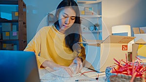 Young Asia businesswoman packing glass use bubble wrap for packing support damage fragile product in home office at night. Small