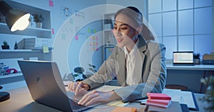 Young Asia cheerful professional businesswoman sitting on desk with laptop computer work online marketing in modern office at