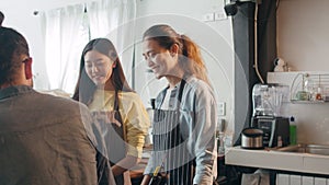 Young Asia female barista serving take away hot coffee paper cup to consumer standing behind bar counter at cafe restaurant. Owner