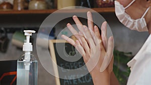 Young Asia female customer wearing protective face mask use hand sanitizer, alcohol gel washer on queueing in restaurant or coffee