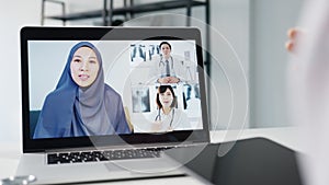 Young Asia female doctor in white medical uniform with stethoscope using computer laptop talking video conference call with